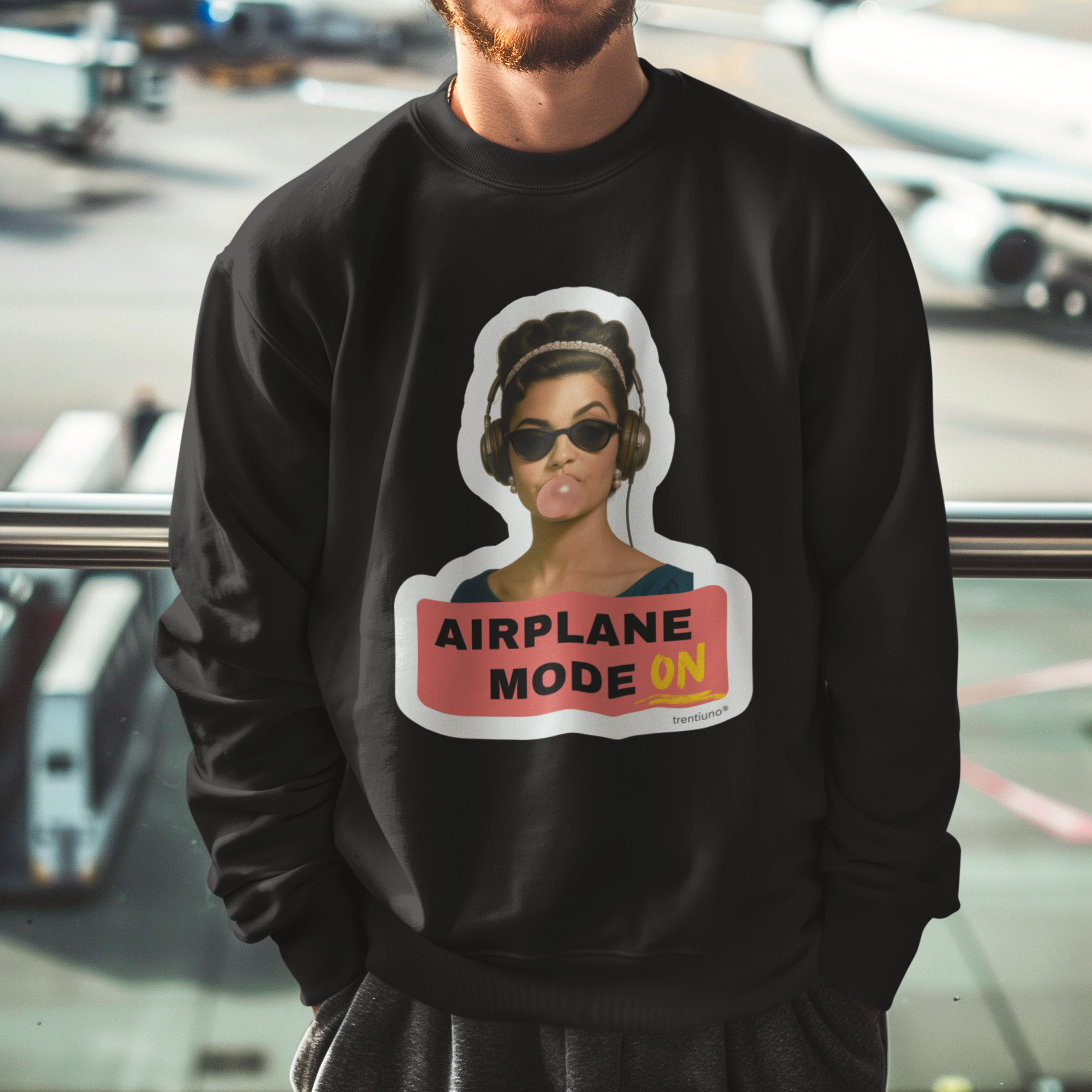 Man wearing a black sweatshirt with an airplane mode graphic at an airport.