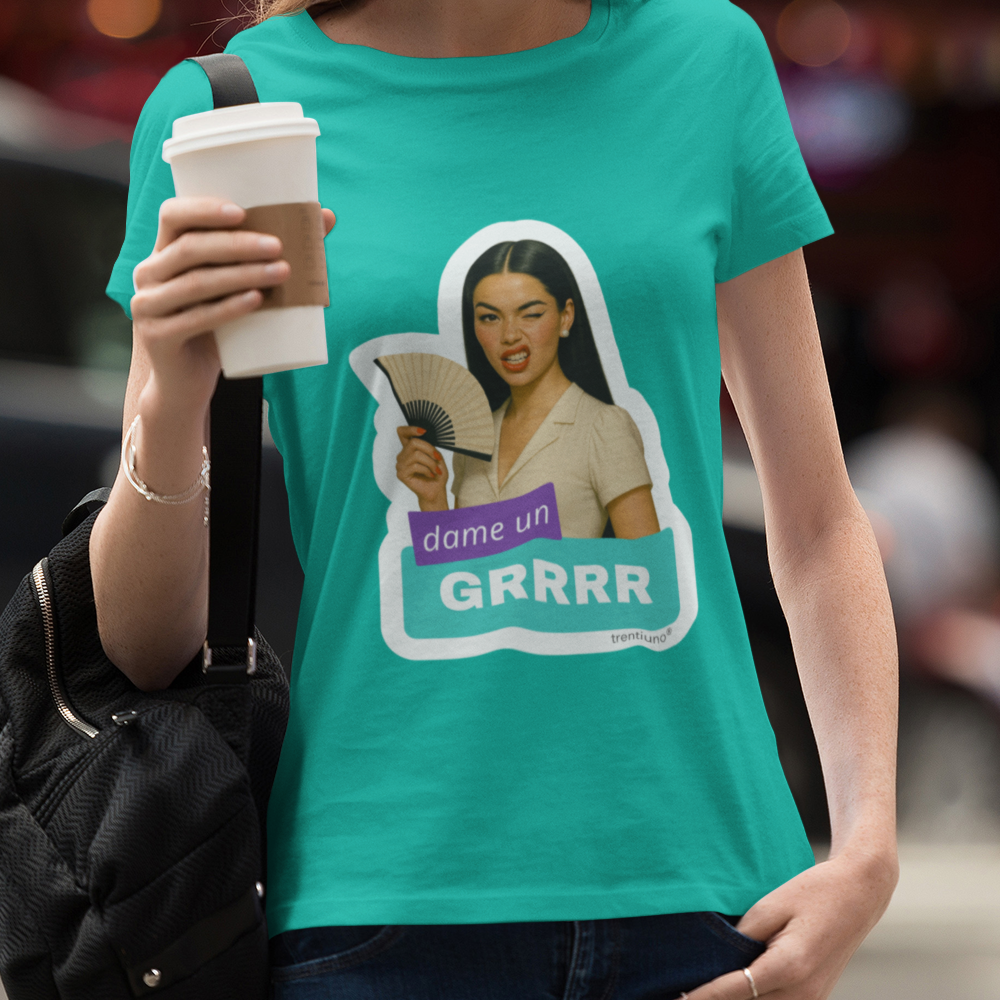 Person wearing a teal t-shirt with a graphic design, holding a coffee cup on a city street.